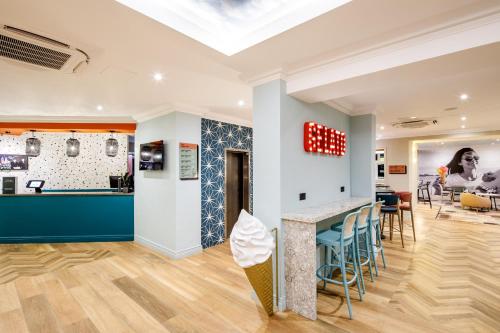 a room with a bar with stools and a table at ibis Styles Bournemouth in Bournemouth