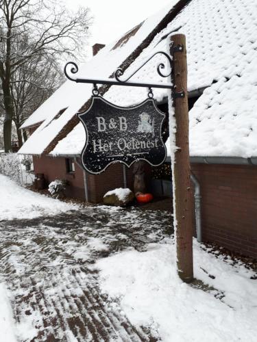 a sign in the snow in front of a house at Bed en Breakfast Het Oelenest in Hooghalen