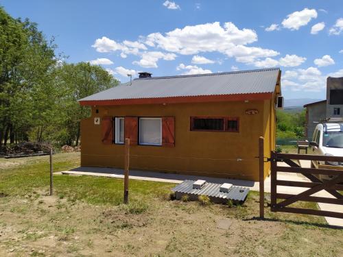 una pequeña casa amarilla con una valla al lado en Vista Bonita en Villa General Belgrano