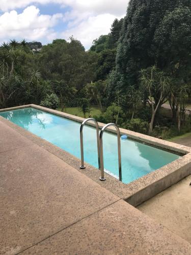 a swimming pool with two metal rails next to trees at BAA BAA RESIDENCE in Hillcrest