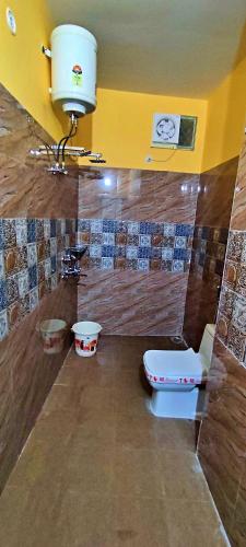 a bathroom with a toilet and a yellow wall at Anandam Home Stay in Rishīkesh
