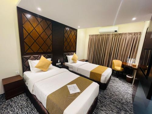 a hotel room with two beds and a desk at Richmond Hotel Sylhet in Sylhet