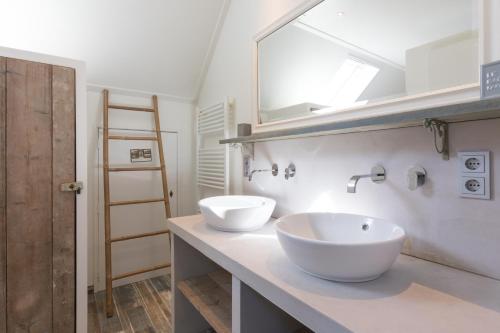 La salle de bains est pourvue de 2 lavabos blancs et d'un miroir. dans l'établissement Hello Zeeland - Vakantiehuis Brouwerijweg 43-4, à Domburg