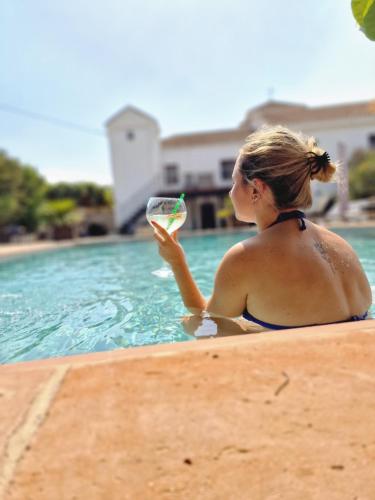 una mujer sentada en la piscina con una copa de vino en El Violin Experiencia Adults only en Melegis