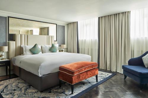 a bedroom with a large bed and a blue chair at The Royal Horseguards Hotel, London in London