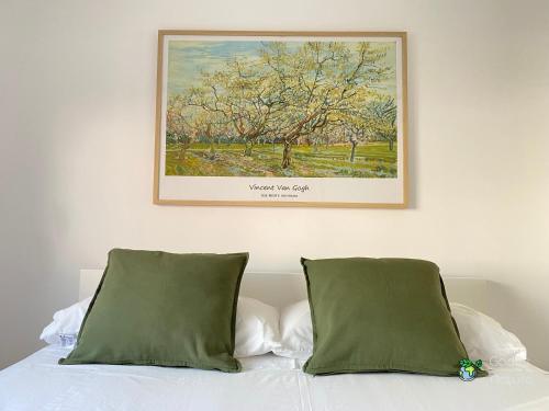 a painting above a bed with two green pillows at Gades Natura Apartment a 450 mts Victoria beach in Cádiz