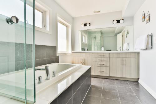 La salle de bains est pourvue d'une baignoire, d'un lavabo et d'un miroir. dans l'établissement 3bdr townhouse in Downsview Park - Free parking - 25 min to Downtown, à Toronto