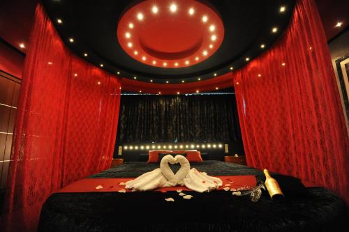 a bedroom with red curtains and a bed with a heart shapedvisor at Carol Hotel in Piraeus