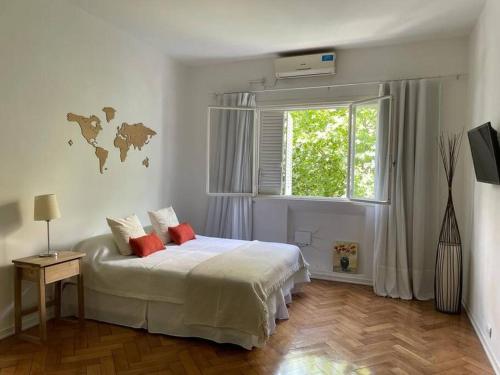Un dormitorio con una cama blanca con almohadas rojas y una ventana en Departamento en pleno Recoleta en Buenos Aires