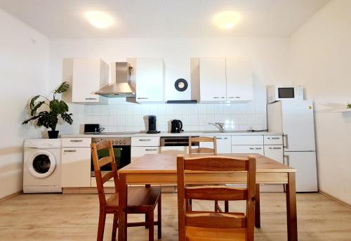 a kitchen with white cabinets and a wooden table and chairs at ELENA flat Sonnenblumen Duisburg Zentrum in Duisburg