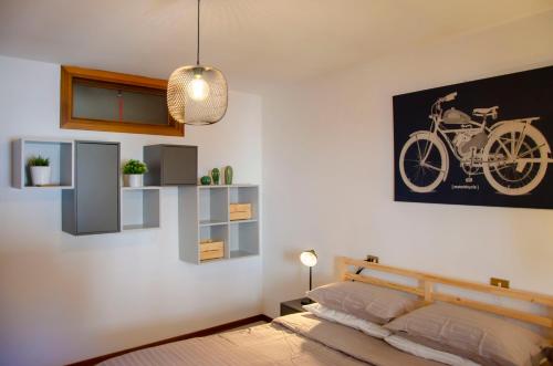 a bedroom with a bed and a picture of a motorcycle on the wall at BBkey La casetta Arta Terme in Arta Terme