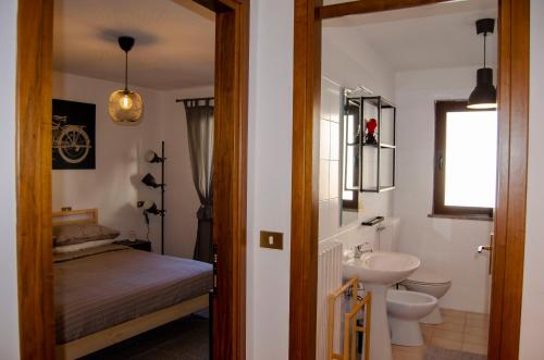 a bathroom with a sink and a toilet and a bed at BBkey La casetta Arta Terme in Arta Terme