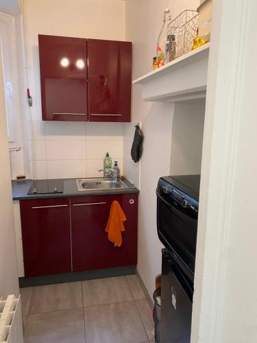 a small kitchen with red cabinets and a sink at Appartement F2 - Paris 18 in Paris