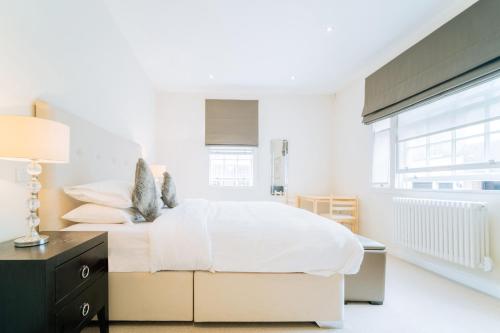 Habitación blanca con cama grande y escritorio. en Clarges - Grand Park Street Apartments, en Londres