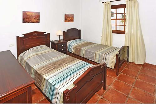 um quarto com 2 camas, uma mesa e uma janela em Villa Don Pedro em Tijarafe