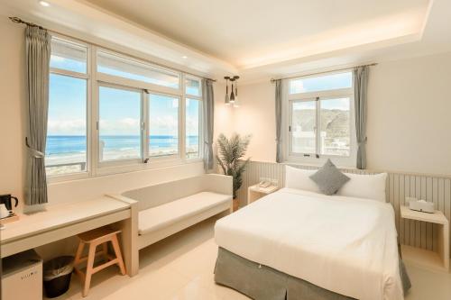 a bedroom with a bed and a bench and windows at Zhudeng 1965 Hotel in Green Island