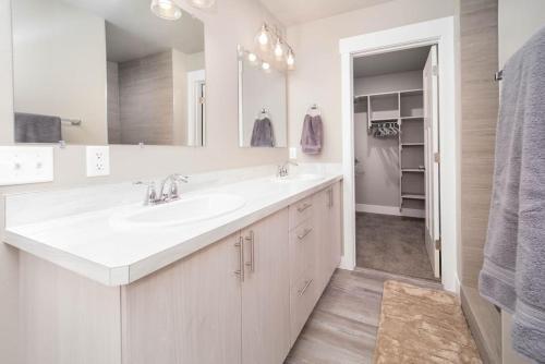 a white bathroom with a sink and a mirror at Delightful, new townhome downtown in Billings