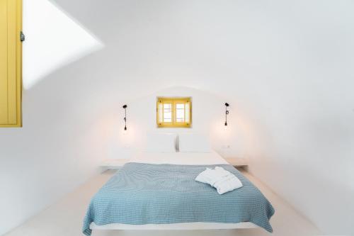 um quarto branco com uma cama com um cobertor azul em Anelia House em Oia