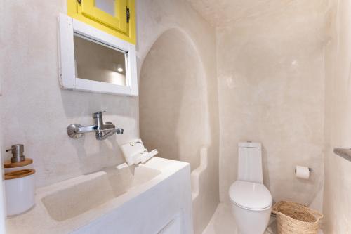 uma casa de banho branca com um lavatório e um WC em Anelia House em Oia