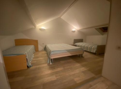a room with two beds and a wooden floor at Gîte du Messager 6/8 personnes in La Machine