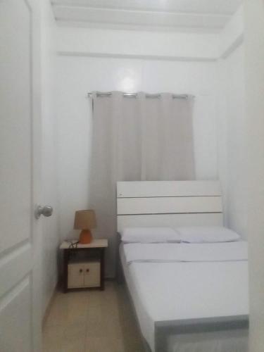 a small white bedroom with a bed and a table at Kendall Place Apartment in Cagayan de Oro