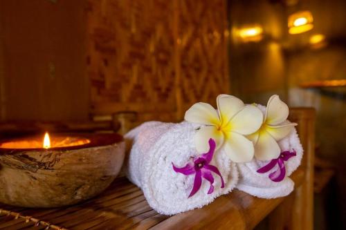 a towel with a flower on it next to a candle at Kingfisher Garden Homestay 2 in Guindulman