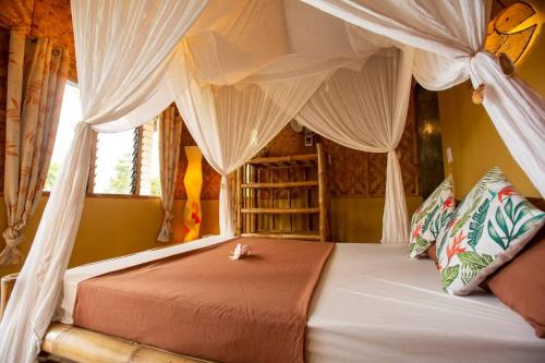 a bedroom with a canopy bed with a cat laying on it at Kingfisher Garden Homestay 2 in Guindulman