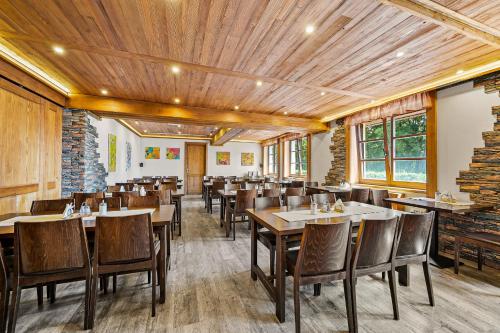 a dining room with wooden ceilings and tables and chairs at David Wellness Hotel in Harrachov