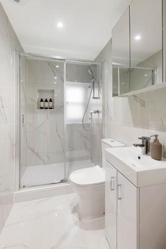 a white bathroom with a shower and a toilet and a sink at Chelsea Apartment | Stamford Bridge, King's Road & River Thames in London