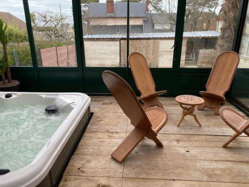 three chairs and a hot tub on a deck at Maison confortable pour 10 personnes avec jacuzzi in Houlgate