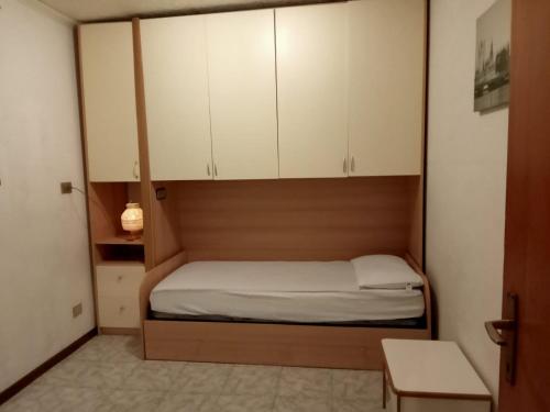 ein kleines Schlafzimmer mit einem Bett und weißen Schränken in der Unterkunft TERRAZZA SULLE DOLOMITI in Castello di Fiemme