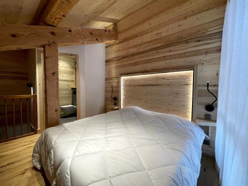 une chambre avec un lit blanc et des murs en bois dans l'établissement GRANDE OURSE bel appartement village et pistes, à La Clusaz