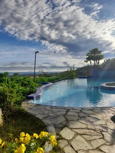 een zwembad met blauw water en gele bloemen bij Hotel Eco Inn Jose in Puerto Píritu