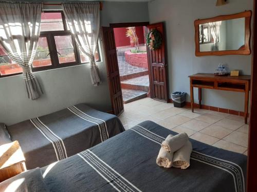 1 dormitorio con 2 camas y un animal de peluche en la cama en posada San Alejandro, en Pátzcuaro
