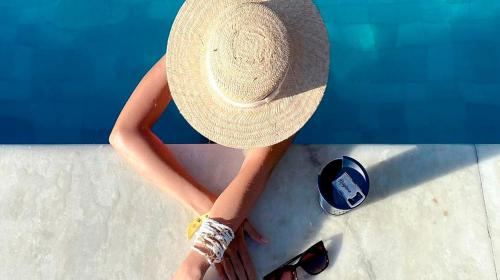 a woman wearing a straw hat sitting next to a pool at Pousada Patuá do Morro in Morro de São Paulo