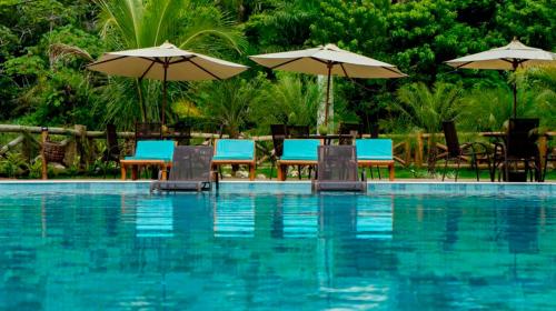 a pool with chairs and tables and umbrellas at Pousada Patuá do Morro in Morro de São Paulo