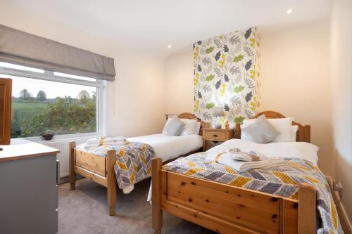 two beds in a small room with a window at Fell View - Dog-Friendly House, Enclosed Garden & Great Views in Penrith