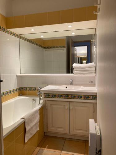 une salle de bain avec une baignoire, un lavabo et un miroir dans l'établissement Les Restanques 103 plein centre, à Grimaud
