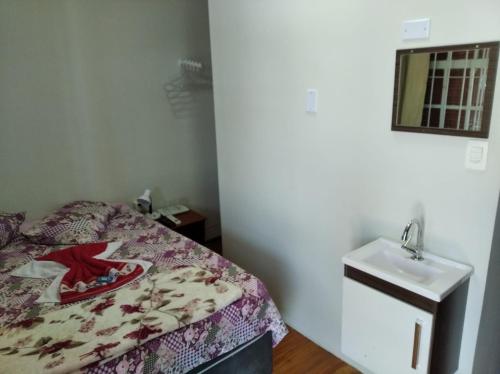 a small bedroom with a bed and a sink at Pousada Seu Jorge in Campinas