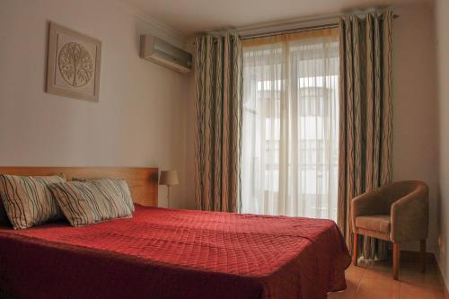 a bedroom with a red bed and a window at Monte da Praia in Monte Gordo