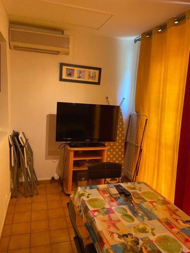 un salon avec une télévision à écran plat et une table dans l'établissement Résidence ALOA - Cap d'Agde, au Cap d'Agde