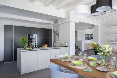 a kitchen with a wooden table and a dining room at 3 Bedroom Modern Villa, Pool, Savoca, East Sicily in Casalvecchio Siculo