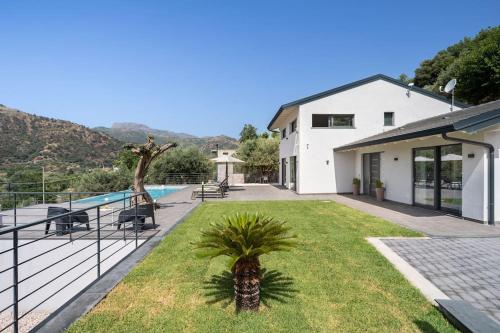a house with a palm tree in the yard at 3 Bedroom Modern Villa, Pool, Savoca, East Sicily in Casalvecchio Siculo