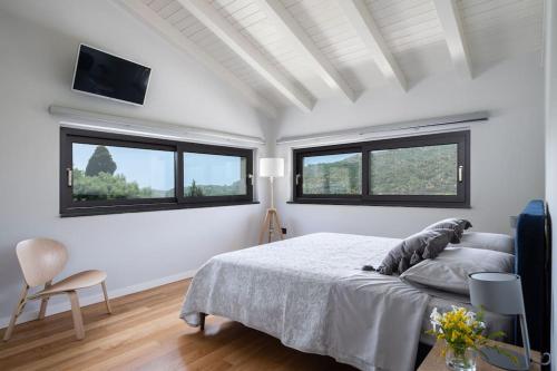 a white bedroom with a bed and two windows at 3 Bedroom Modern Villa, Pool, Savoca, East Sicily in Casalvecchio Siculo