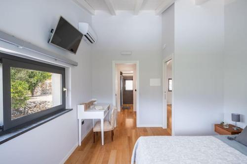 a bedroom with a bed and a desk and a tv on a wall at 3 Bedroom Modern Villa, Pool, Savoca, East Sicily in Casalvecchio Siculo