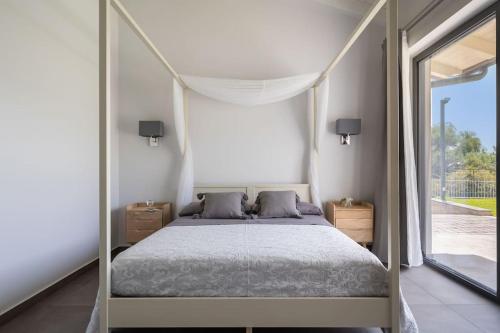 a bedroom with a canopy bed and a large window at 3 Bedroom Modern Villa, Pool, Savoca, East Sicily in Casalvecchio Siculo
