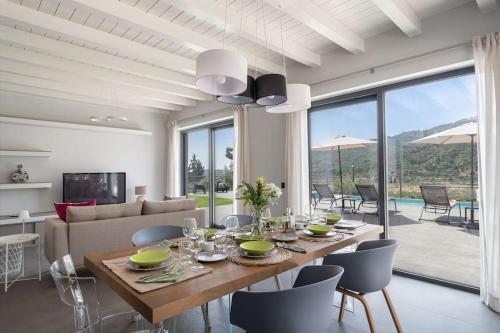 a dining room with a table and chairs and a living room at 3 Bedroom Modern Villa, Pool, Savoca, East Sicily in Casalvecchio Siculo