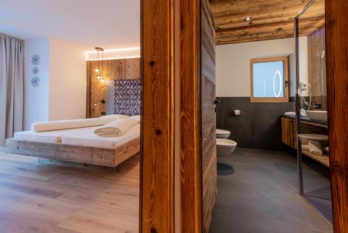 1 dormitorio con 1 cama grande y baño en Apartments Ciasa Costisela, en San Vigilio Di Marebbe