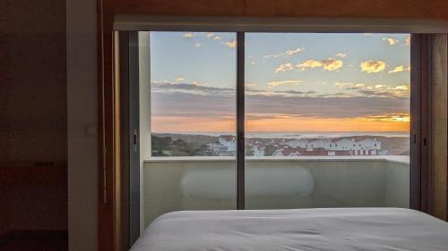 a bedroom with a window with a view of the sunset at Duplex by the Beach in Ovar