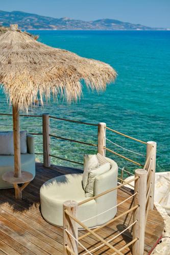 a chair and an umbrella on a deck with the ocean at Paradisso Beach Villas in Zakynthos Town